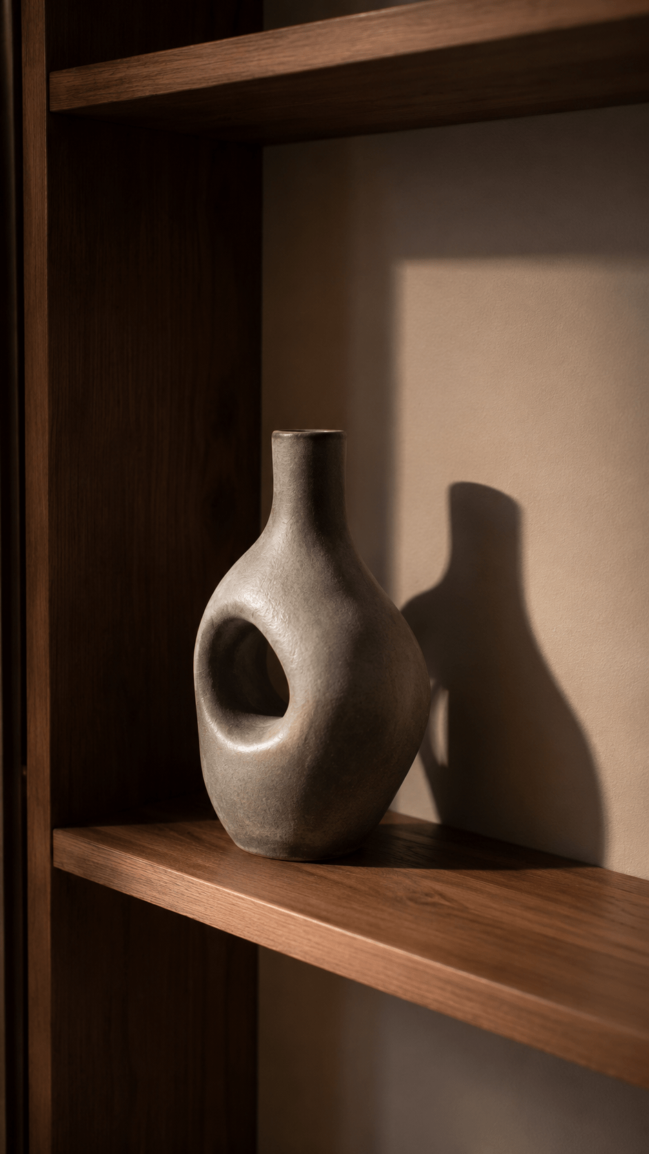 sculptural ceramic vase anchoring a styled wood living room shelf, placed off-center